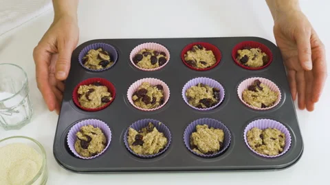 Muffin batter in silicon cups on baking sheet. Bran muffins with dry cranberries Stock Footage 136723955