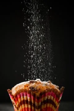 Muffin in icing sugar on a black background. The process of making homemade.. Stock Photos