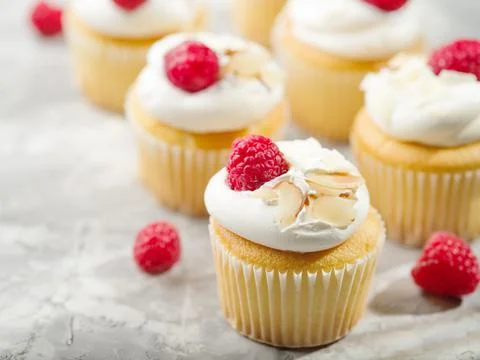 Muffins decorated with cream, raspberries, almonds. Isolated on white backgro Stock Photos