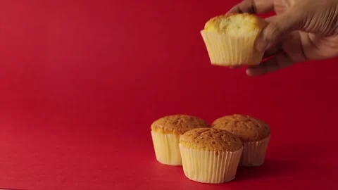 Muffins or cupcakes kept together. hand picking one muffin and having a bite. Stock Footage 219973587