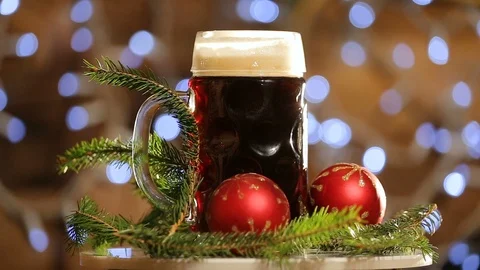 A mug of beer with bright lights bokeh rotates. Christmas dark beer Stock Footage 99699615