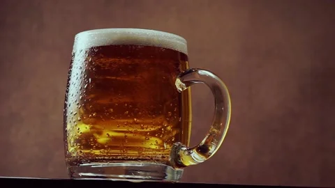 Mug with beer on dark brown background. Low point of view Stock Footage 135699386