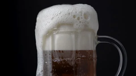 Mug of beer with fizzy bubbles and froth on a black background, Stock Footage 251640643