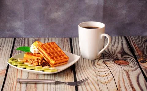 A mug of black coffee and a plate of waffles in vanilla cream with slices of Stock Photos