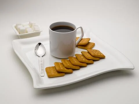 Mug of black tea in serving plate with sugar cubes and biscuits India Stock Photos