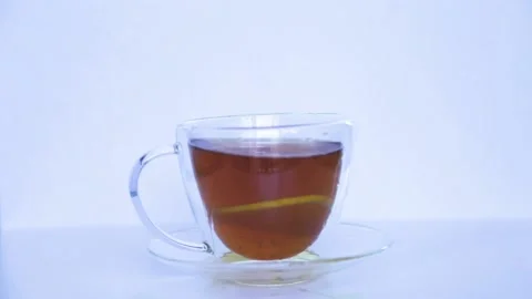 A mug of black tea stands on a white background, a ring of yellow lemon is Stock Footage 161696186