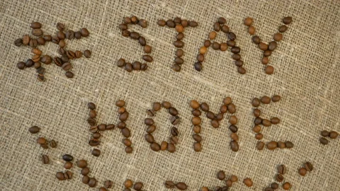 Mug of coffee, coffee beans, and words stay home, coronavirus concept, self h Video stock 129387599