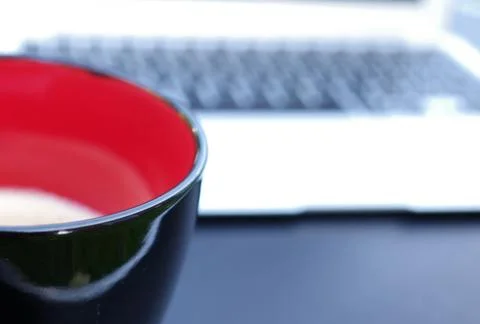 A mug with coffee in front of a laptop 库存照片