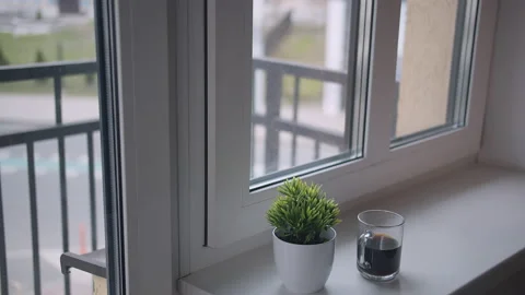 A mug of coffee is on the windowsill, outside the window the traffic and people Stock Footage 160018397