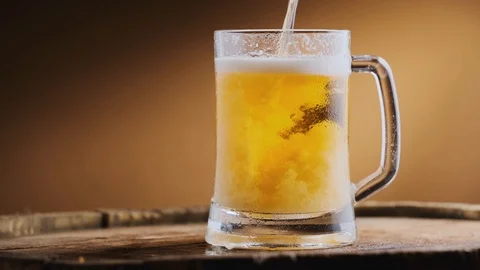 Mug of cold light beer rotates on a wooden barrel. Stock Footage 125638453