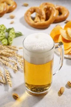 A mug of draft beer and various snacks around. Stock Photos