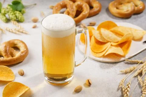 A mug of draft beer and various snacks around. Stock Photos