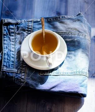 Mug filled boiling water and tea bag on blue jeans background. Process tea Stock Photos