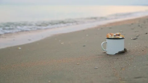 Mug filled with shells standing on shore against male legs running along shore Video stock 93110744