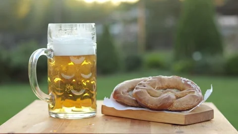 Mug of fresh beer with foam and homemade pretzels on a wooden table. Oktoberfest Stock Footage 317539457