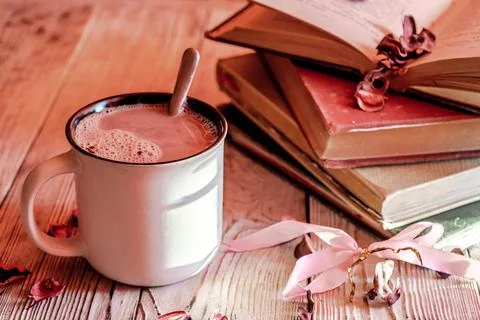 Mug of hot chocolate near a stack of vintage old books on wooden rustic table Stock Photos