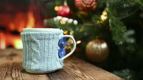 Mug with a hot drink in a knitted case on a wooden table against the background Stock Footage 220134454