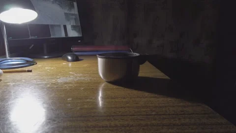 A mug of hot tea or coffee on a table lit by a lamp in front of a computer Stock Footage 168628662