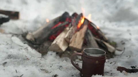 A mug of hot tea stands by the fire in a snowy forest Stockbeeldmateriaal 169747421