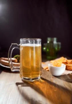 A mug of light beer on a dark background with snacks. Close-up Stock Photos