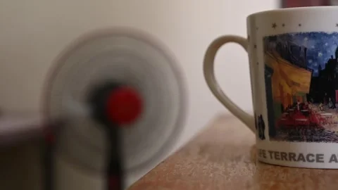Mug with Oscillating Fan in Background on a Hot Day Stock Footage 346486884