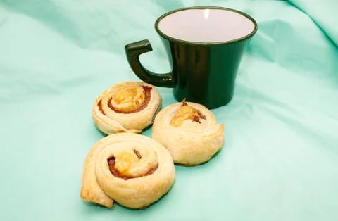 A mug on the table, next to which are three baked buns on a turquoise backgro Foto stock