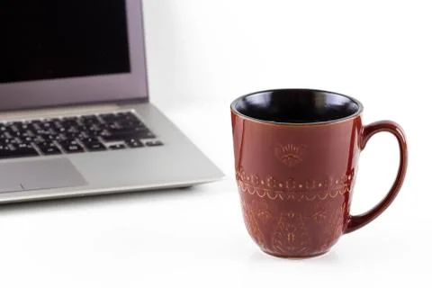 A mug of tea on a white table next to a laptop. Stock Photos