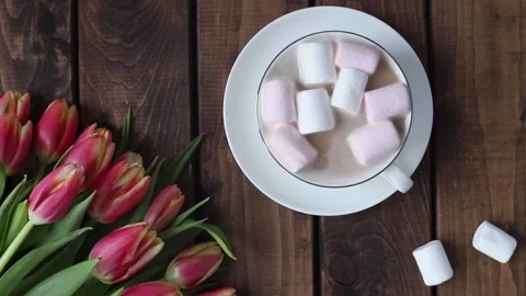 A mug of tea on a wooden table next to a bouquet of tulips Stock Footage 213808699