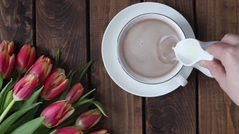 A mug of tea on a wooden table next to a bouquet of tulips Stock Footage 213808722