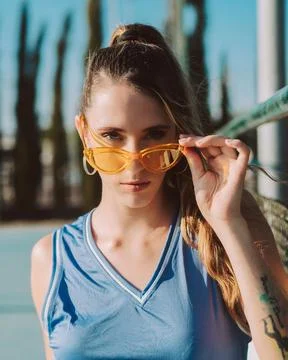 Mujer joven con gafas de sol naranjas y ropa deportiva Stock Photos