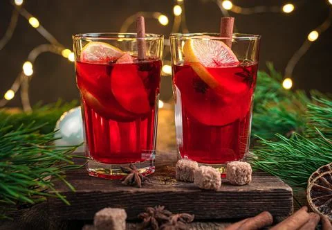 Mulled wine on the background of pine branches and Christmas lights. Stock Photos