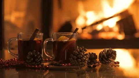 Mulled wine glasses on table in front of burning fireplace. Stock Footage 79874365
