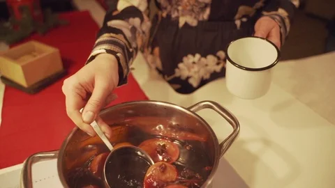 Mulled wine is poured into mugs on the table among Christmas decorations, slow Stock Footage 100979320