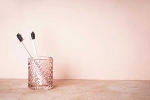 Multi-co Two toothbrushes in a glass with space for text, on a beige backgrou Stock Photos