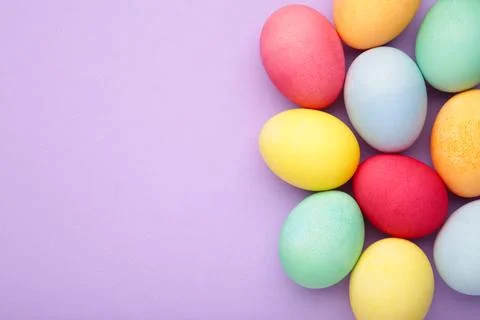 Multi color eggs on purple background. Stock Photos