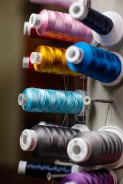 Multi color small spools of sewing thread stacks on large cylinder display Fotos de archivo