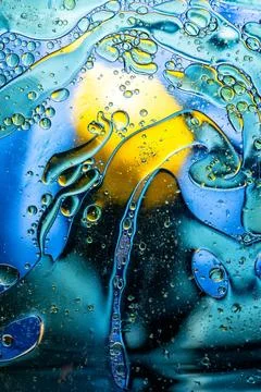 Multi colored abstract oil bubbles on water vibrant blue and yellow mix Stock Photos
