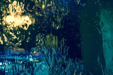 Multi-colored abstraction: water flowing down the glass with reflection of ni Stock Photos
