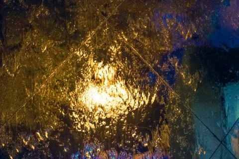 Multi-colored abstraction: water flowing down the glass with reflection of ni Stock Photos