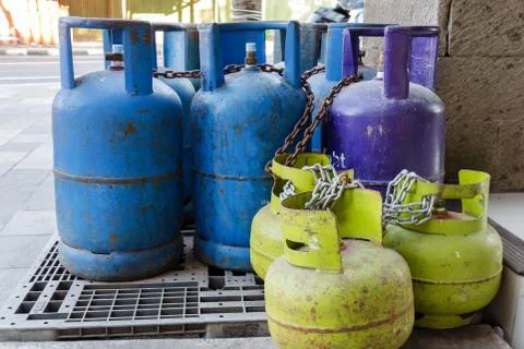 Multi-colored and different-sized gas cylinders on the street. Stock Photos