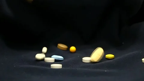 Multi-colored and varied pills take off on a black background close-up Stock Footage 337426883