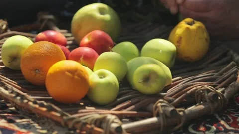 Multi-colored apples and oranges lie on a wicker plate. Sunny day. Video stock 216117158