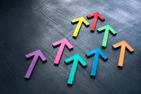 Multi-colored arrows on a dark surface as a symbol of teamwork and unity. Stock Photos