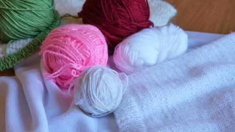 Multi-colored balls of pink, red, green and white yarn lie on a soft white Stock Photos