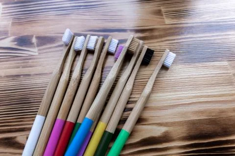 Multi-colored bamboo toothbrushes lie on a wooden background. eco friendly. Stock Photos