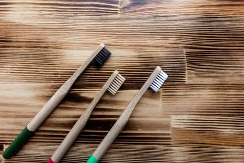 Multi-colored bamboo toothbrushes lie on a wooden background. eco friendly. Stock Photos