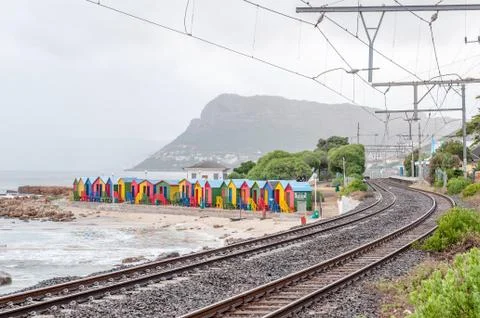 Multi-colored beach huts at St. James with railroad passing by Stock Photos