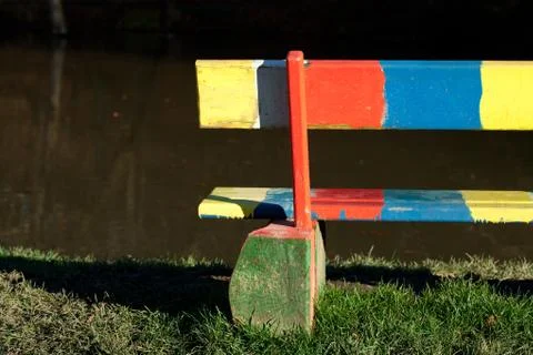 Multi-colored bench standing in a park near the pond Stock Photos