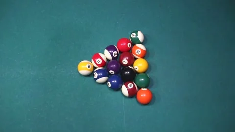 Multi-colored billiard balls in a triangle scatter on a green table from above Stock Footage 339029229
