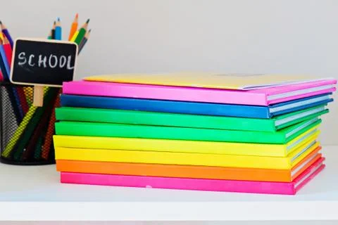 Multi colored books in stack on the light-coloured bookshelf Stock Photos